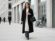 Woman wearing a knit midi dress layered over trousers and a wool coat